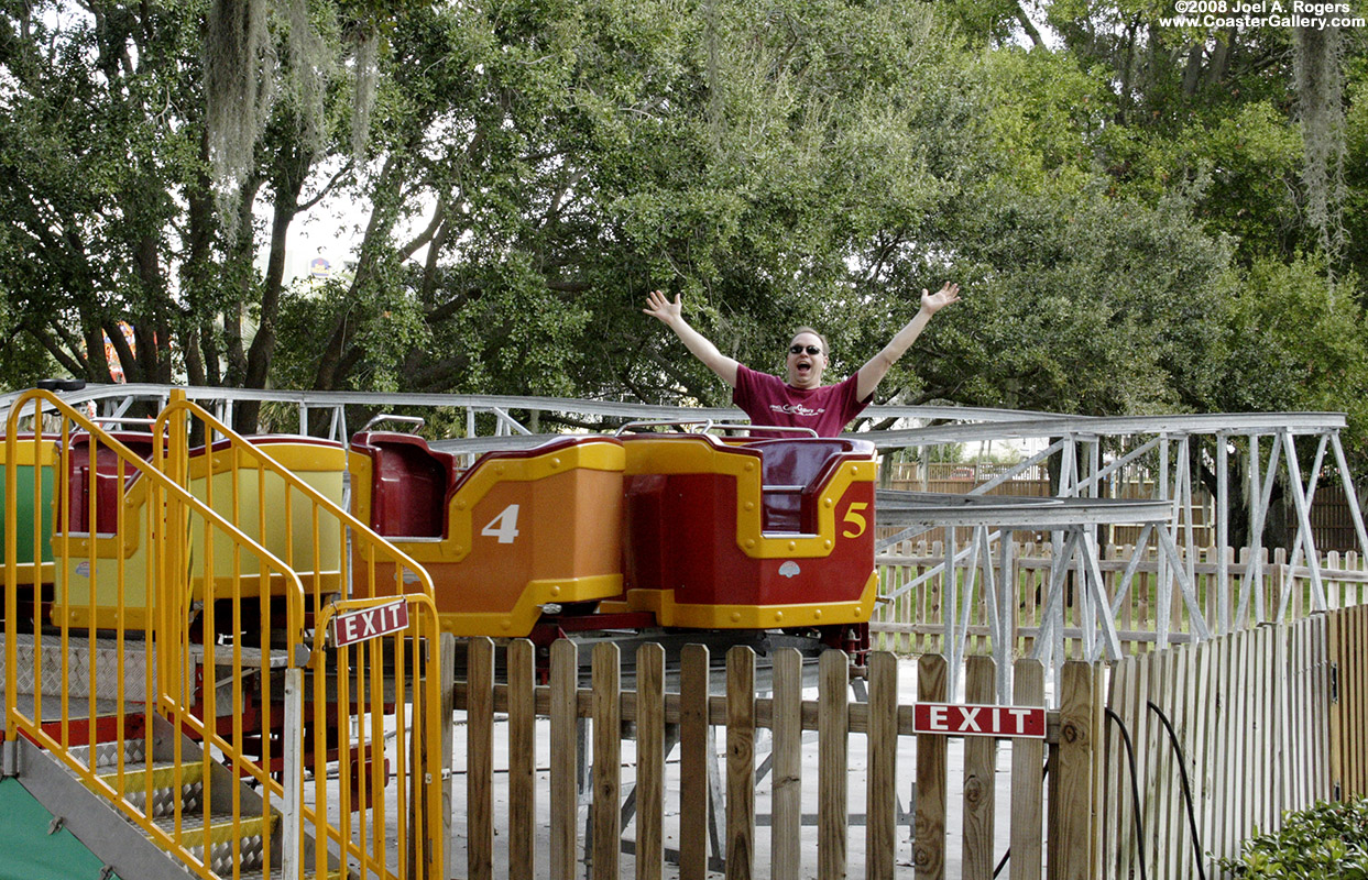 Joel A. Rogers riding a kiddie coaster while wearing a CoasterGallery shirt