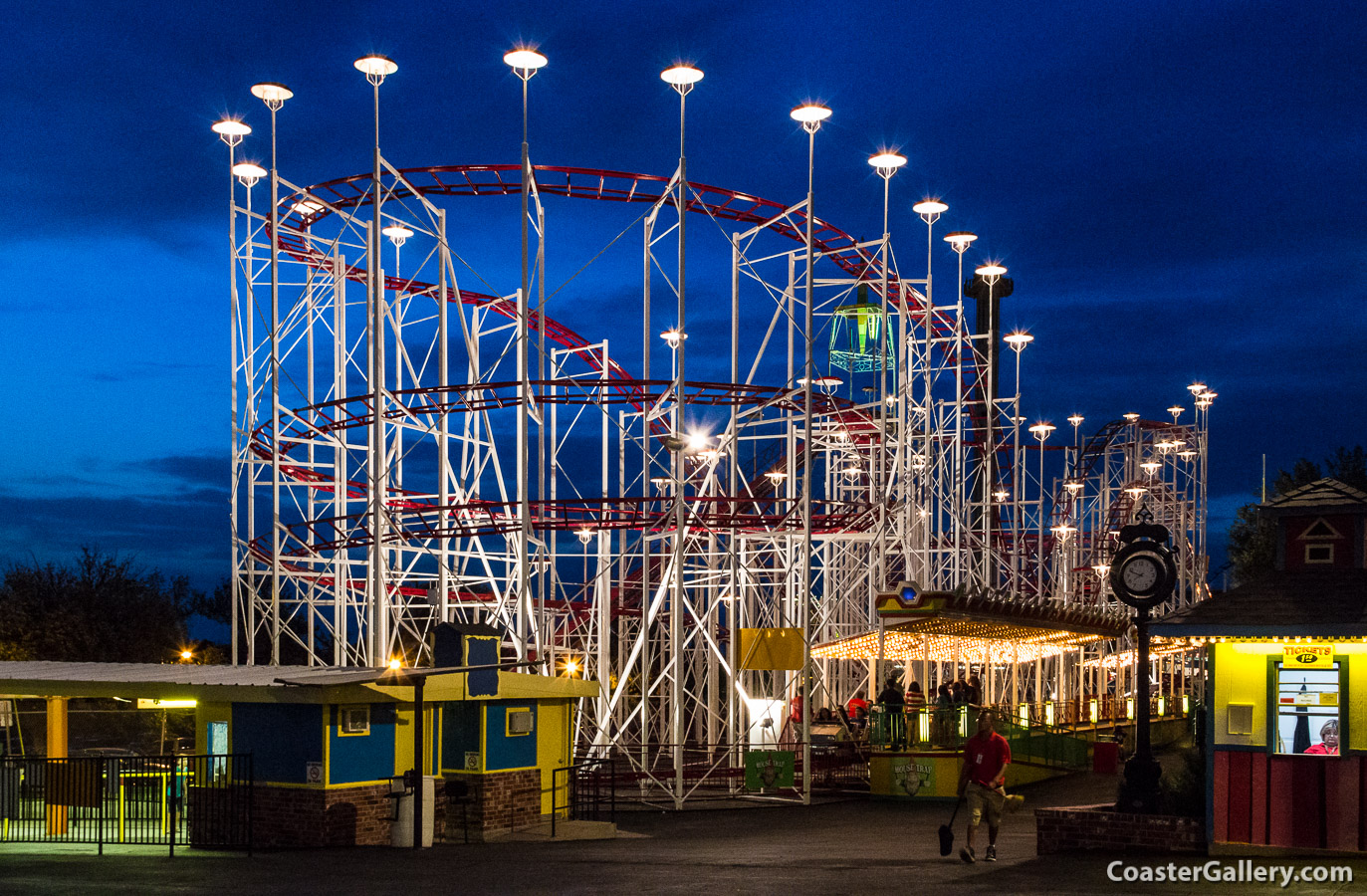 An amusement park and roller coaster lit up at night.