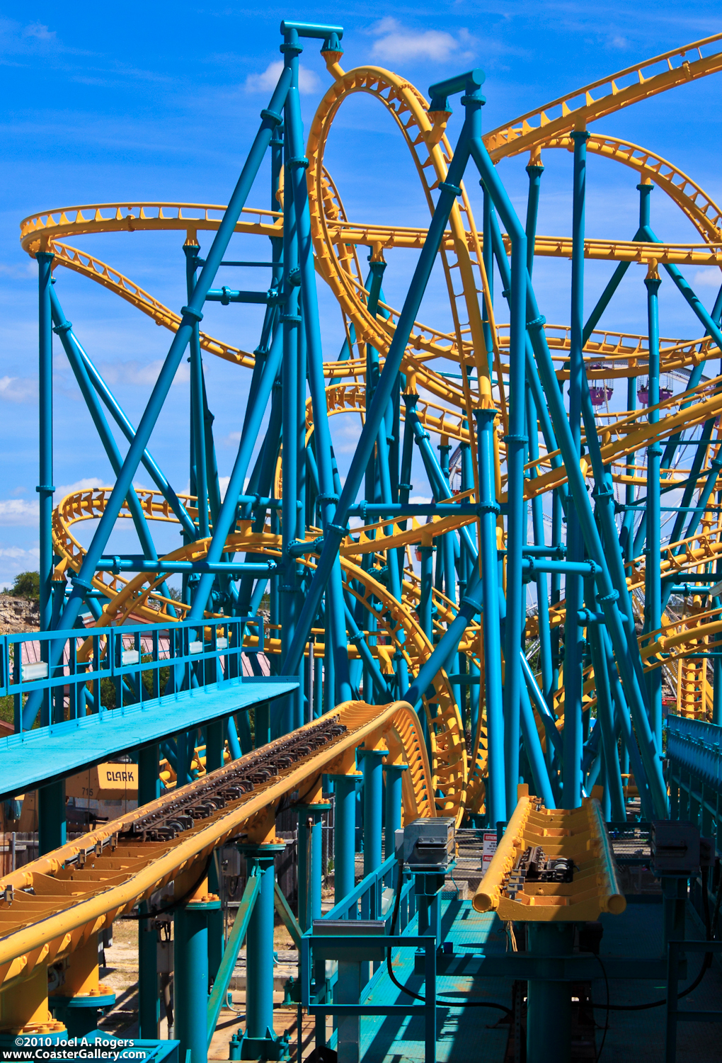 Stock image of a looping yellow and blue roller coaster at Six Flags - Cobra Roll, Sidewinder, and Corkscrew loops