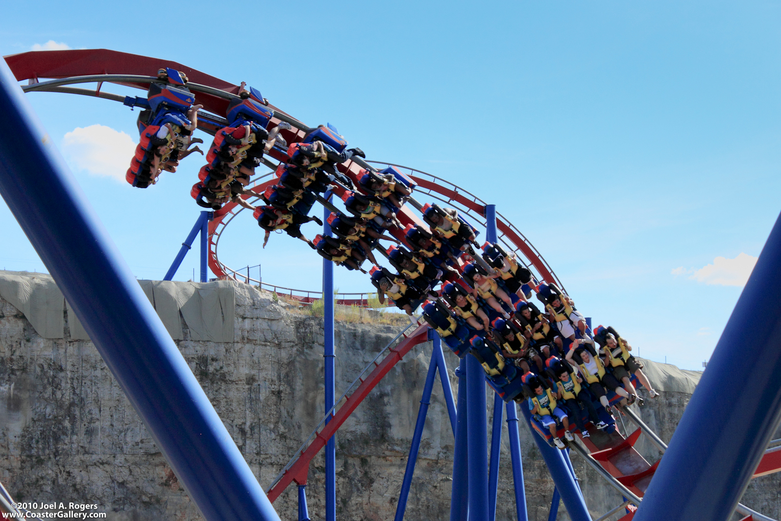 A floorless roller coaster train, track and cliff wall.