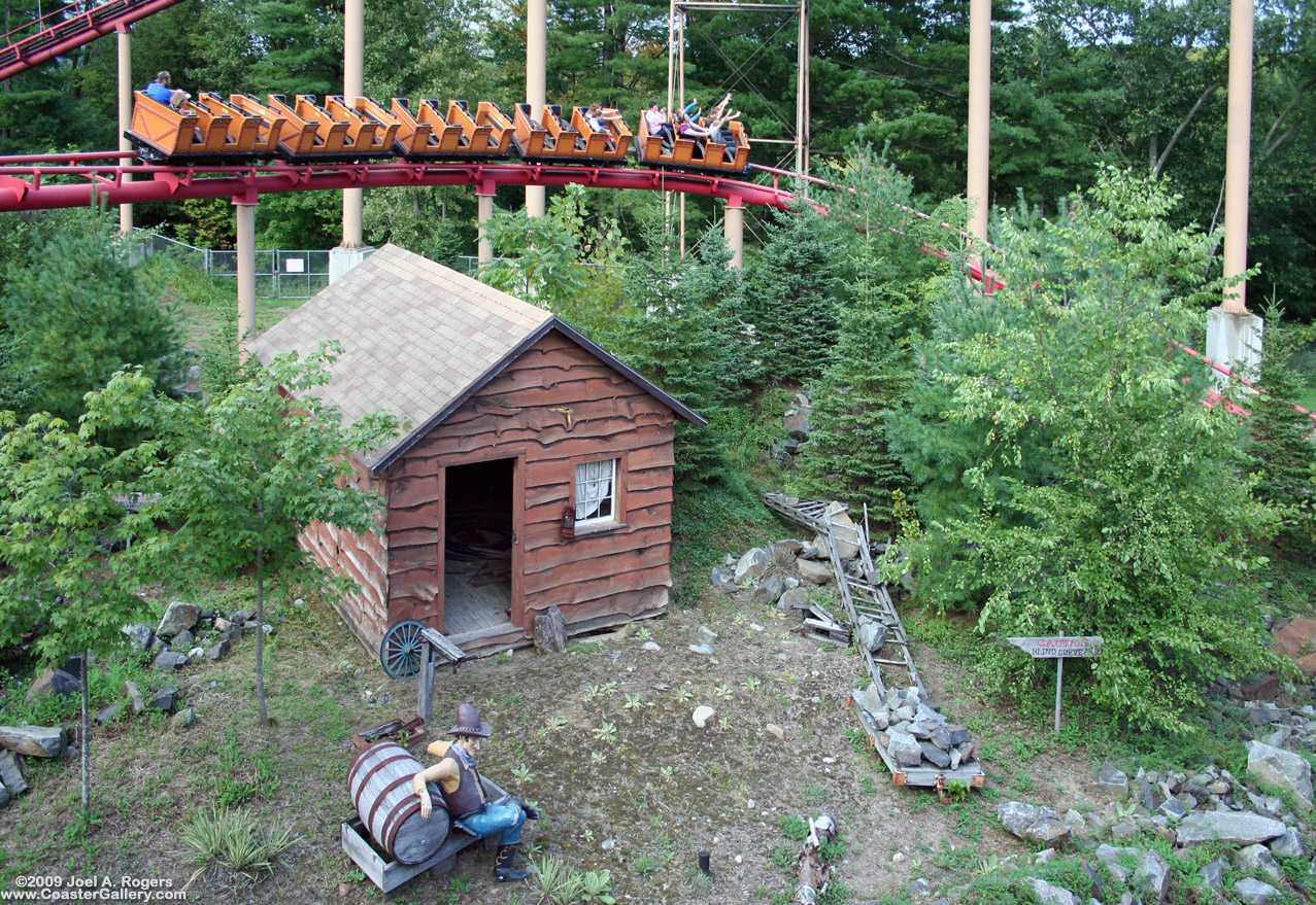 Decorations and buildings next to a old fashioned Mine Train roller coaster