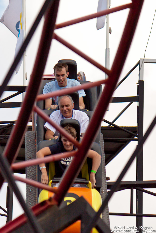 Three men riding in a little roller coaster car