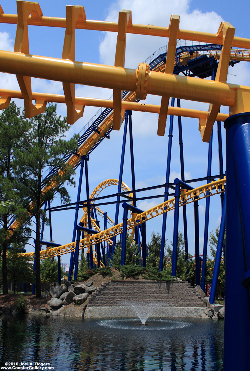 A flying roller coaster looping over the water and a fountain