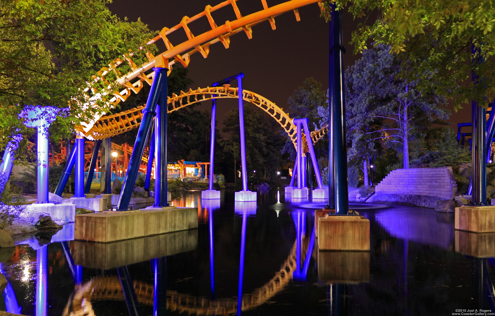 A roller coaster reflected in the water at night